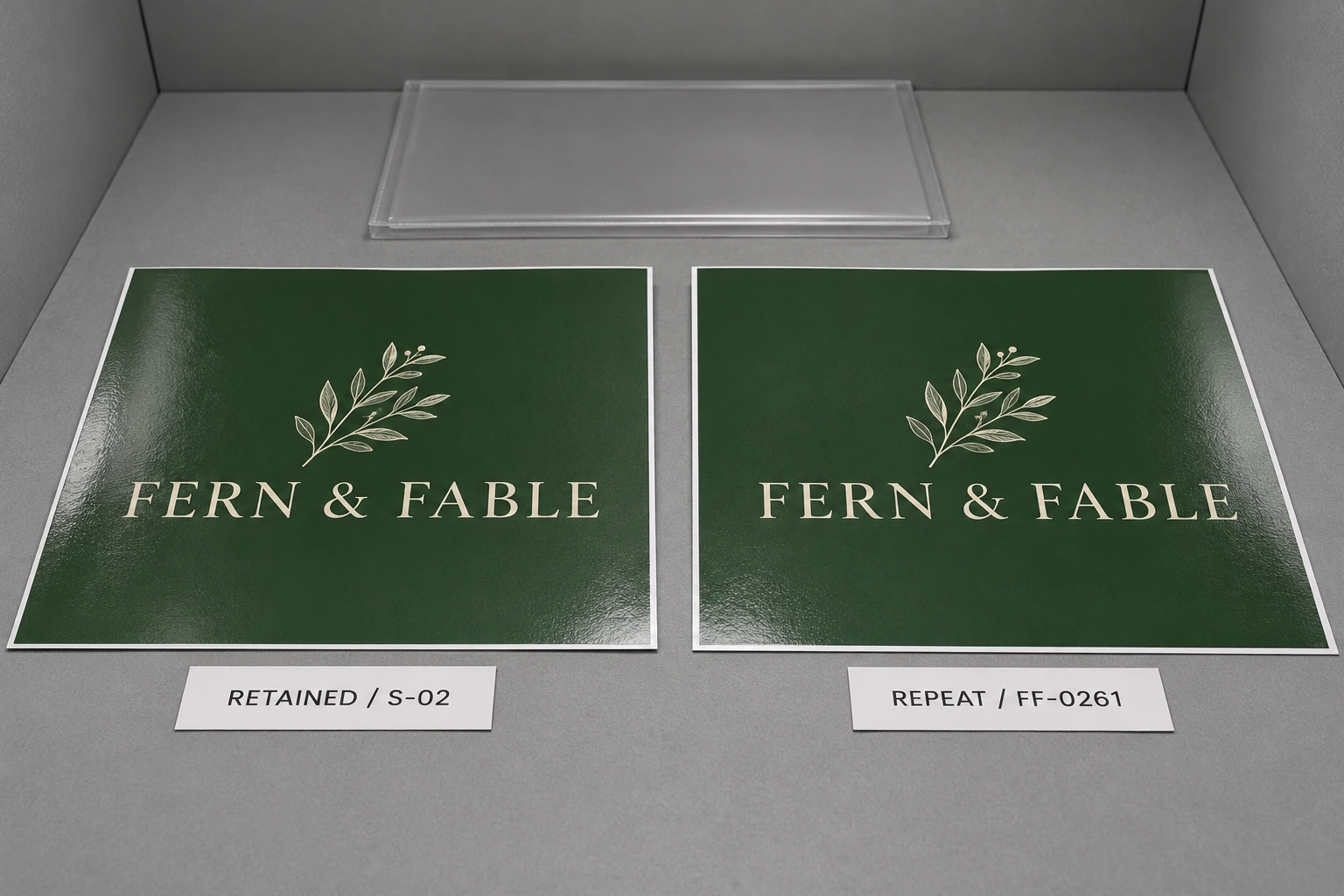 Two fictional Fern & Fable printed samples labeled retained S-02 and repeat FF-0261 in a neutral-gray viewing enclosure.